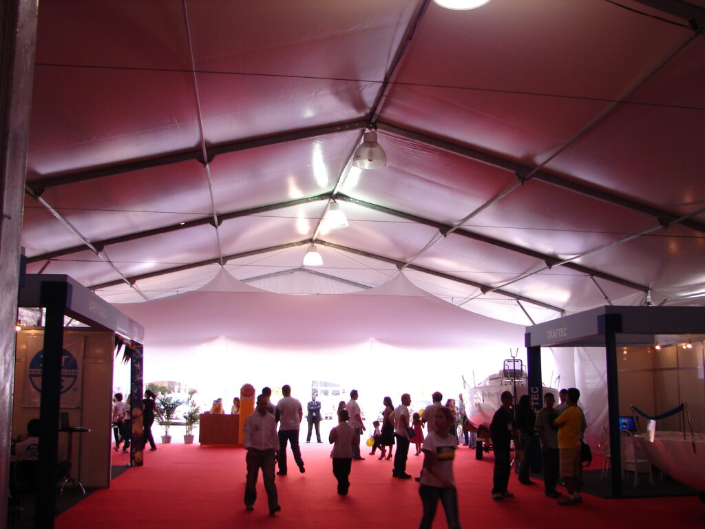 Interior de tenda duas águas montada para evento, com carpete e iluminação cênica