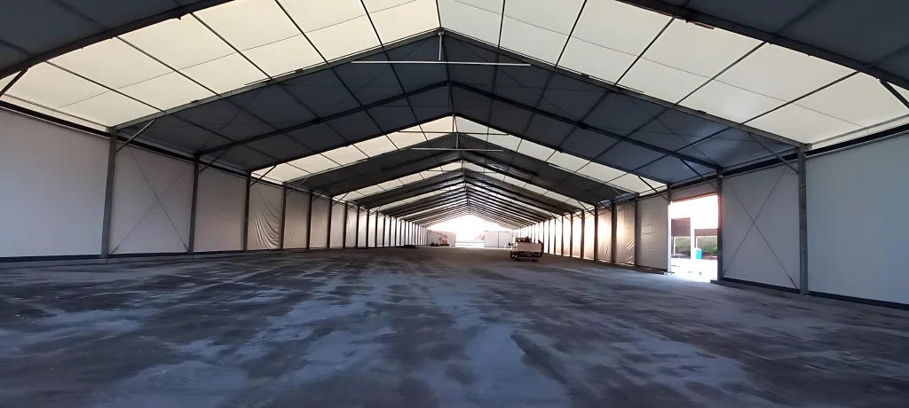 Interior vazio de galpão de lona duas águas com piso de concreto