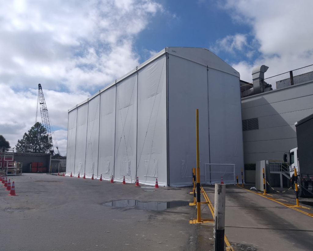Cobertura lonada acoplada à lateral de um prédio industrial